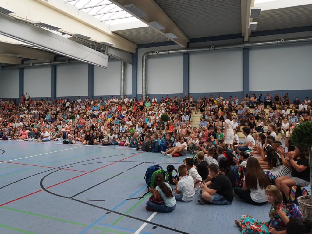 Kinder sitzen in der Mitte der Halle.
